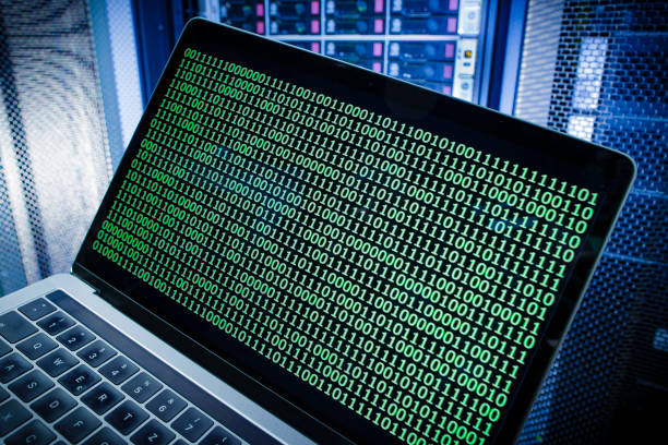 BERLIN, GERMANY - JANUARY 12: Symbolic photo with topic online crime, data theft and piracy: A man poses with a laptop showing a binary code in front of Server racks in a server center on January 12, 2018, in Berlin, Germany. (Photo Illustration by Thomas Trutschel/Photothek via Getty Images)